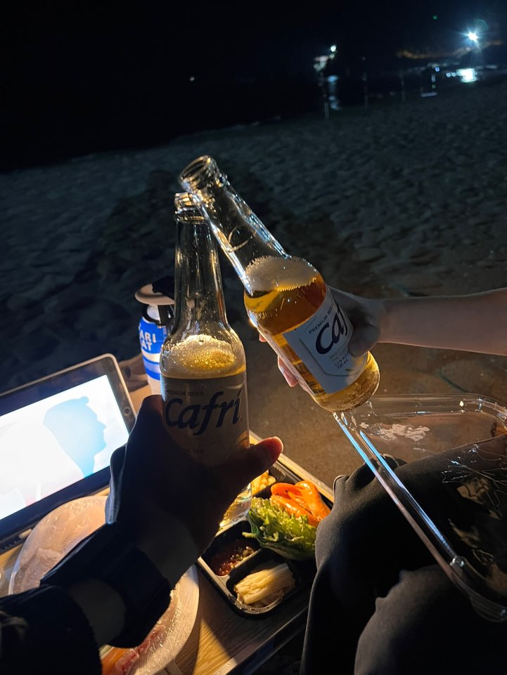밤 맹방해변에서 맥주병으로 건배하는 모습